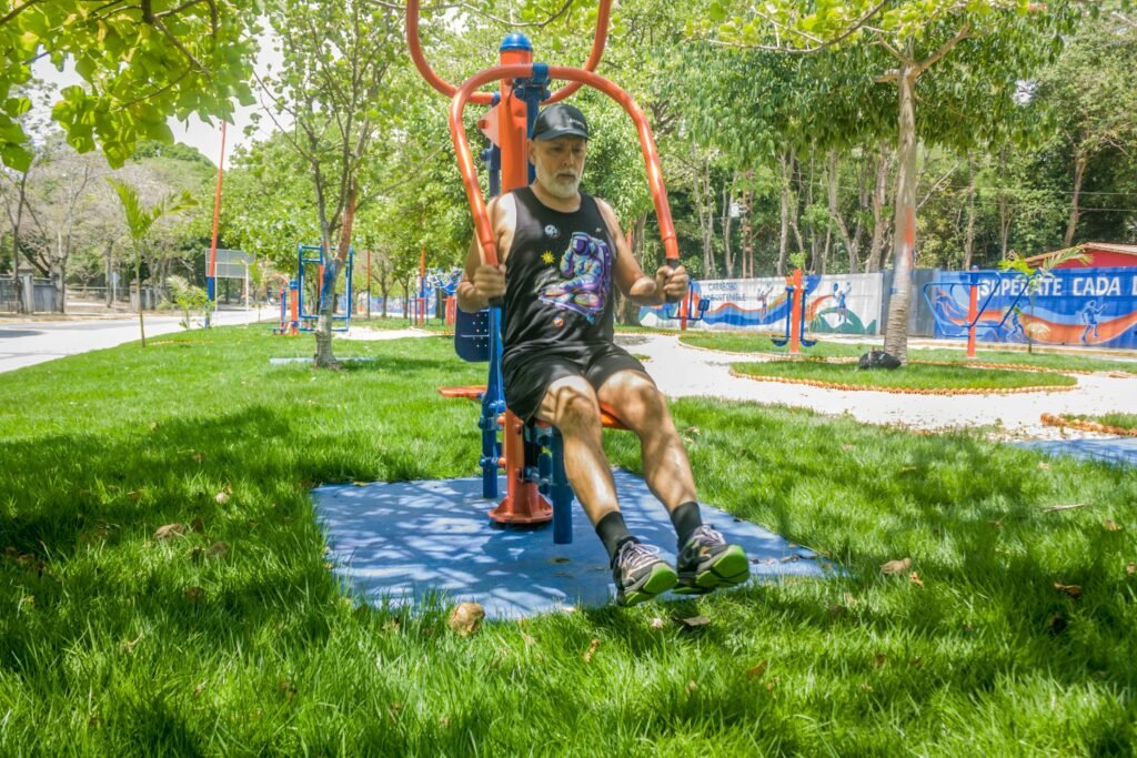 Older man performing strength exercise on outdoor gym equipment in a park